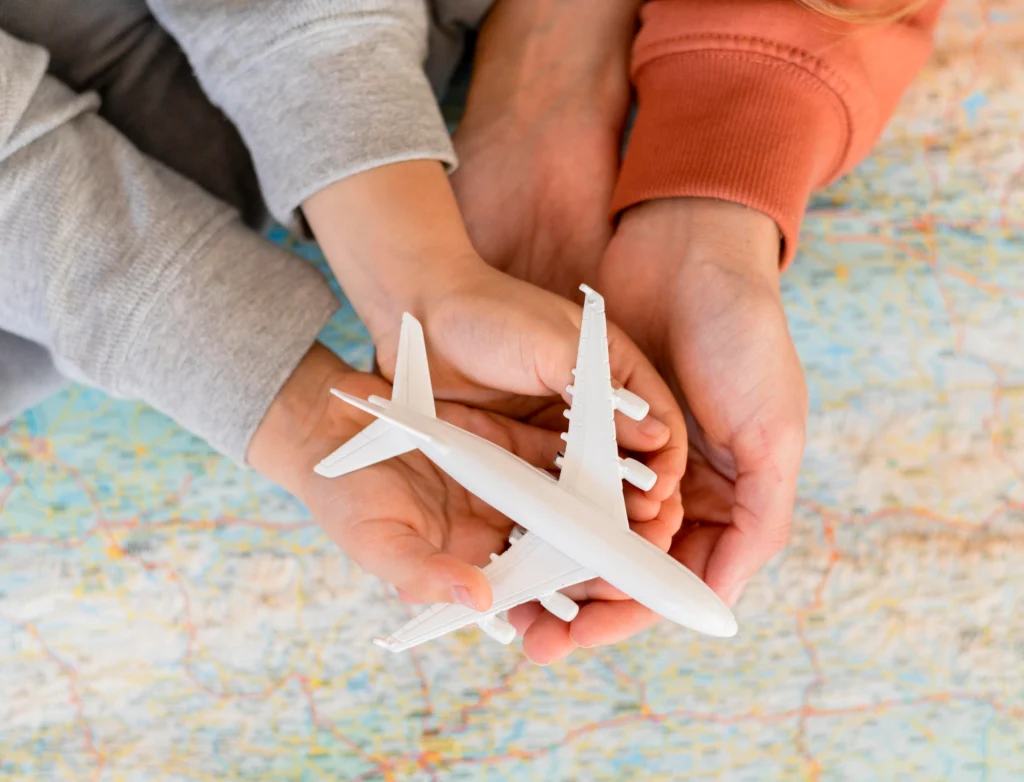 Manos de una familia sosteniendo un avión: símbolo de viajar en avión con niños