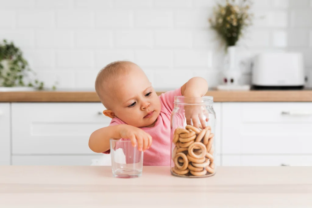 Niño pequeño tomando galletas del tarro con autonomía e independencia.
