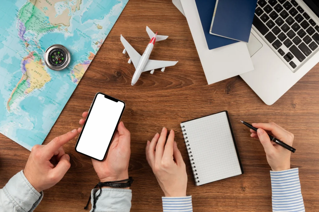 Personas en un escritorio con celular y cuaderno buscando información sobre las Políticas por Aerolíneas